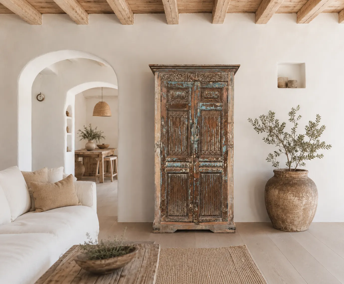 Ibiza, Bohemian & Oosterse kasten – teakhouten vitrinekast in landelijk bohemian interieur Ibiza-stijl vitrinekast van teakhout met glazen deuren in een bohemian en oosters interieur met olijftak, aardewerken kruiken en juten vloerkleed.